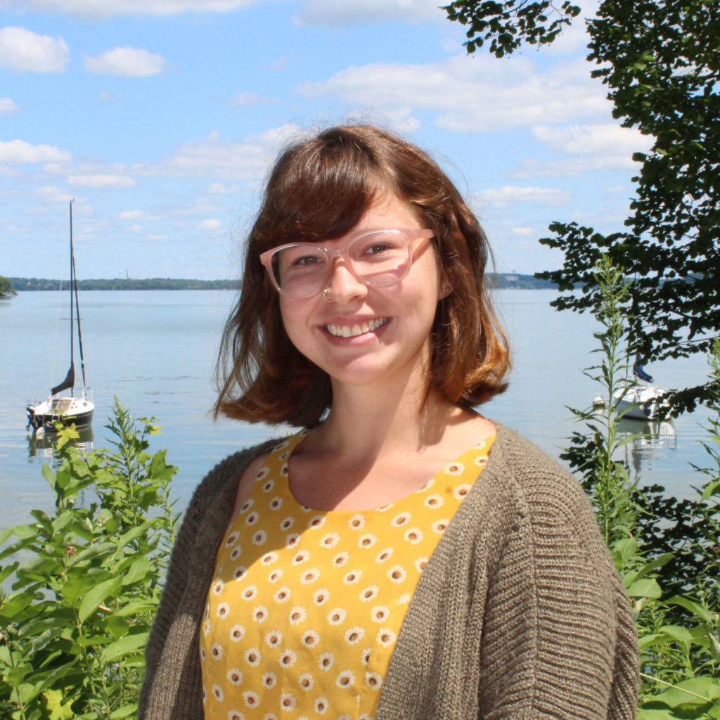 Smiling woman standing in front of a lake.