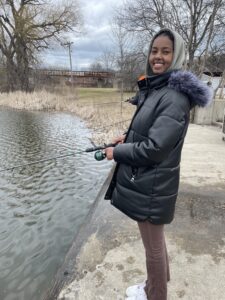 smiling woman in winter coat fishing