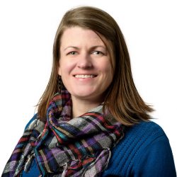 Close-up a smiling person wearing a plaid scarf and blue shirt.