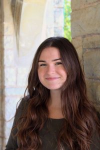 Close up of smiling person leaning against a wall