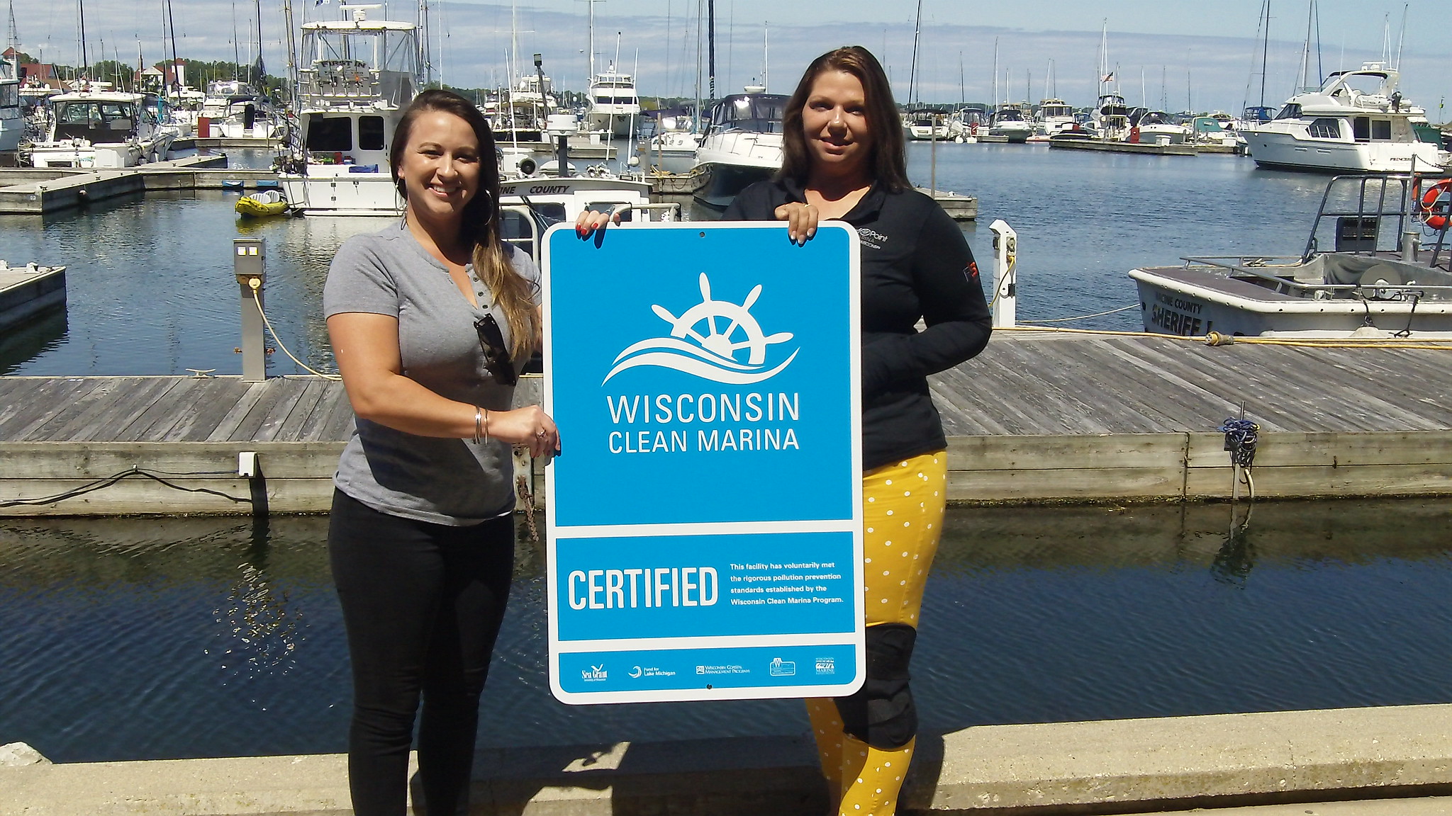 Two smiling people holding a sign that says Wisconsin Clean Marina
