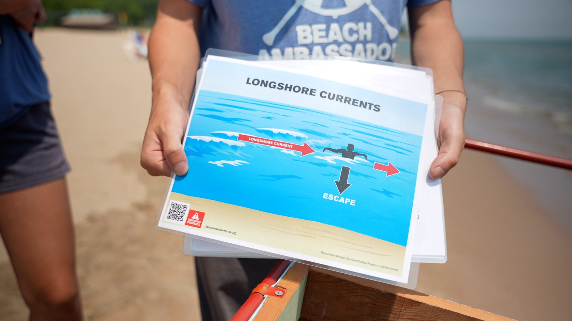 A Beach Ambassador shows a informative flyer about longshore currents