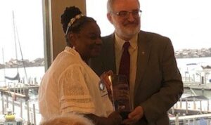 Two people standing side by side jointly holding a shiny award.