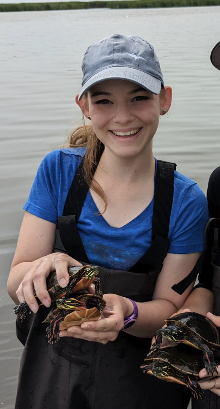 Gweni Malokofsky in waders holding up painted turtles