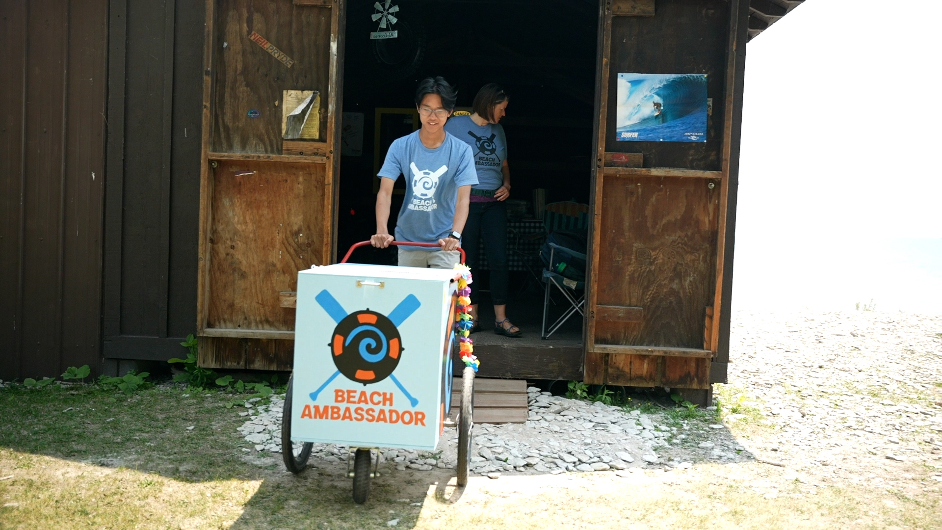 Alan Lian g pushes the blue Beach Ambassador cart from the shed.