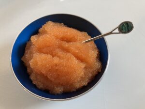 Dish and small spoon. Dish contains orange-pink fish eggs, known as caviar. 