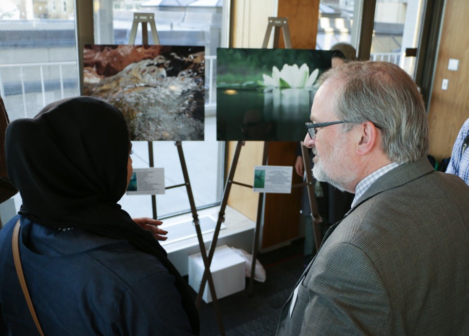 Jim Hurley chats with another gallery-goer in front of a photo of a water lily.