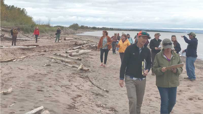 Participants on a Coastal Hazards of Superior (CHAOS) field trip learning more about spotting signs of erosion at Shaefer Beach in Superior, Wis.