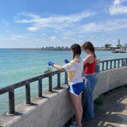 Two undergraduate students collect water samples from Lake Michigan