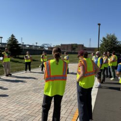 A tour group in high visibility vests looks at permeable pavement