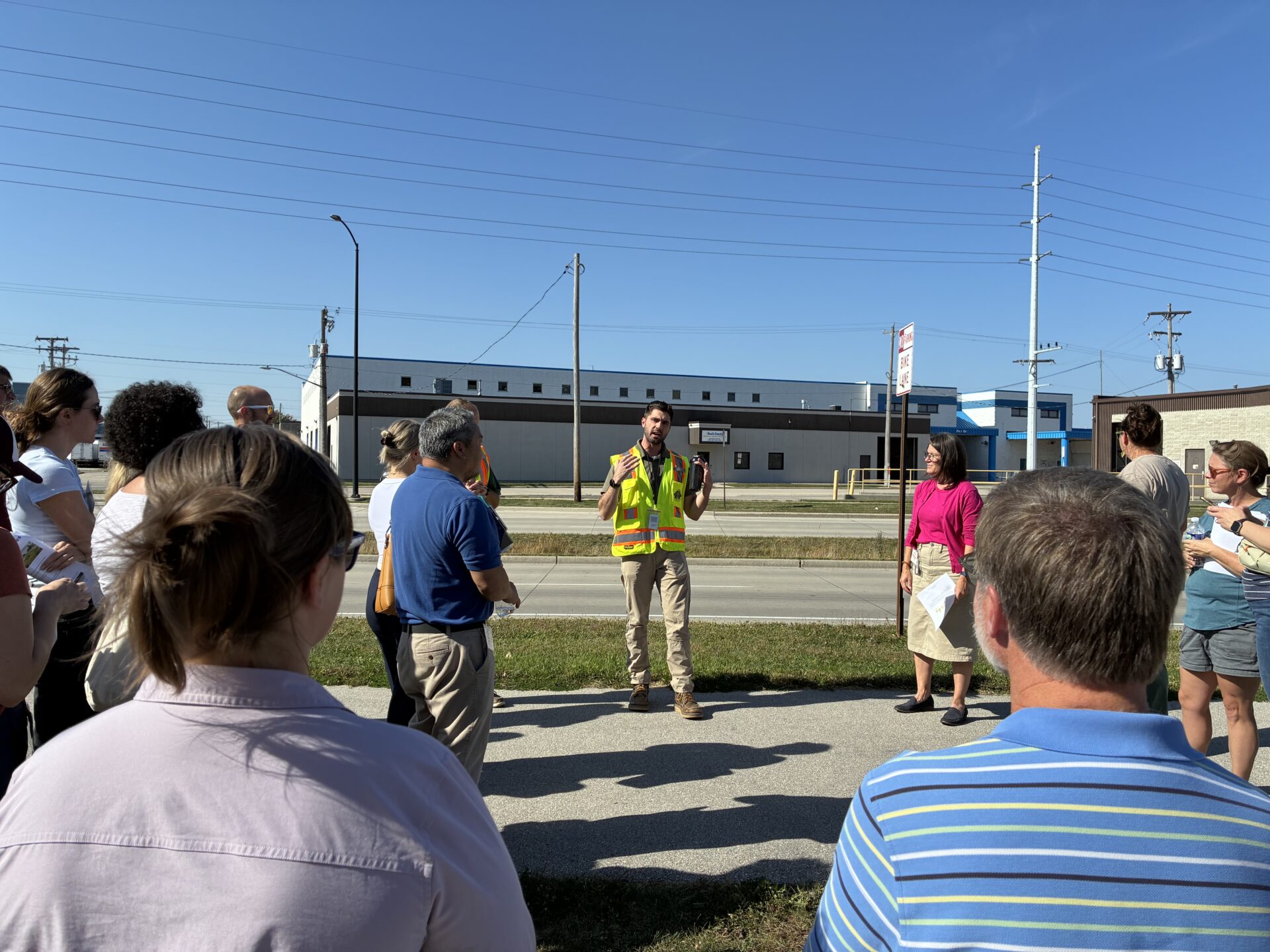 A stormwater engineer in a bright yellow vest explains how bioswales catch stormwater on Webster Avenue in Green Bay.
