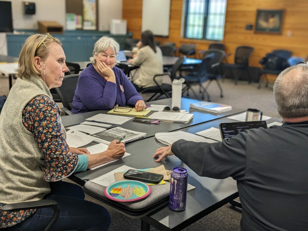 Three people discuss around a table at the workshop.