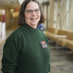 A woman with short dark hair, glasses, and a green sweater wearing a Sea Grant nametag